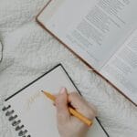 Notatnik przy otwartej Biblii i filiżance kawy na kocu