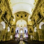 Wnętrze kościoła z wysokimi sklepieniami, łukami i bogato zdobionym ołtarzem