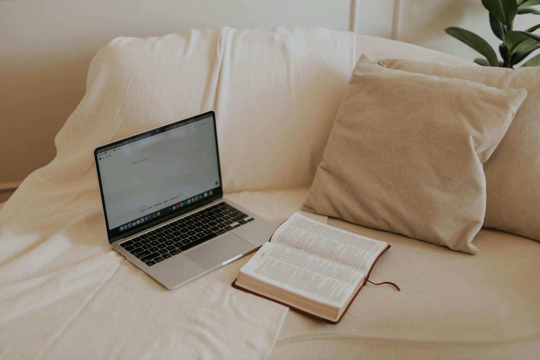 Otwarta Biblia i laptop na sofie w domowym miejscu do czytania Pisma