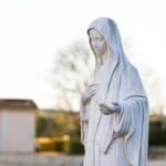 Maryja w historii Polski i naszej parafii: dlaczego tak często powierzamy Jej rodziny, miasto i Ojczyznę? Figura Matki Bożej w Medjugorju oświetlona światłem zachodu słońca