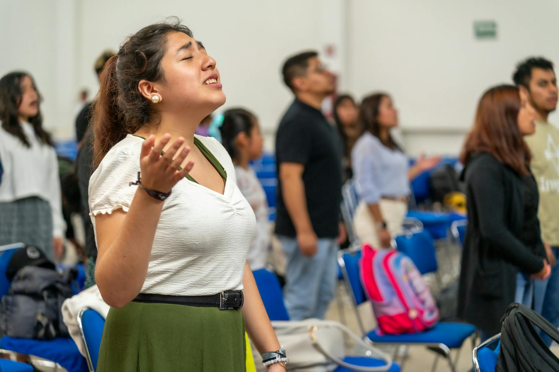Młodzi dorośli z uniesionymi rękami podczas modlitwy we wspólnocie