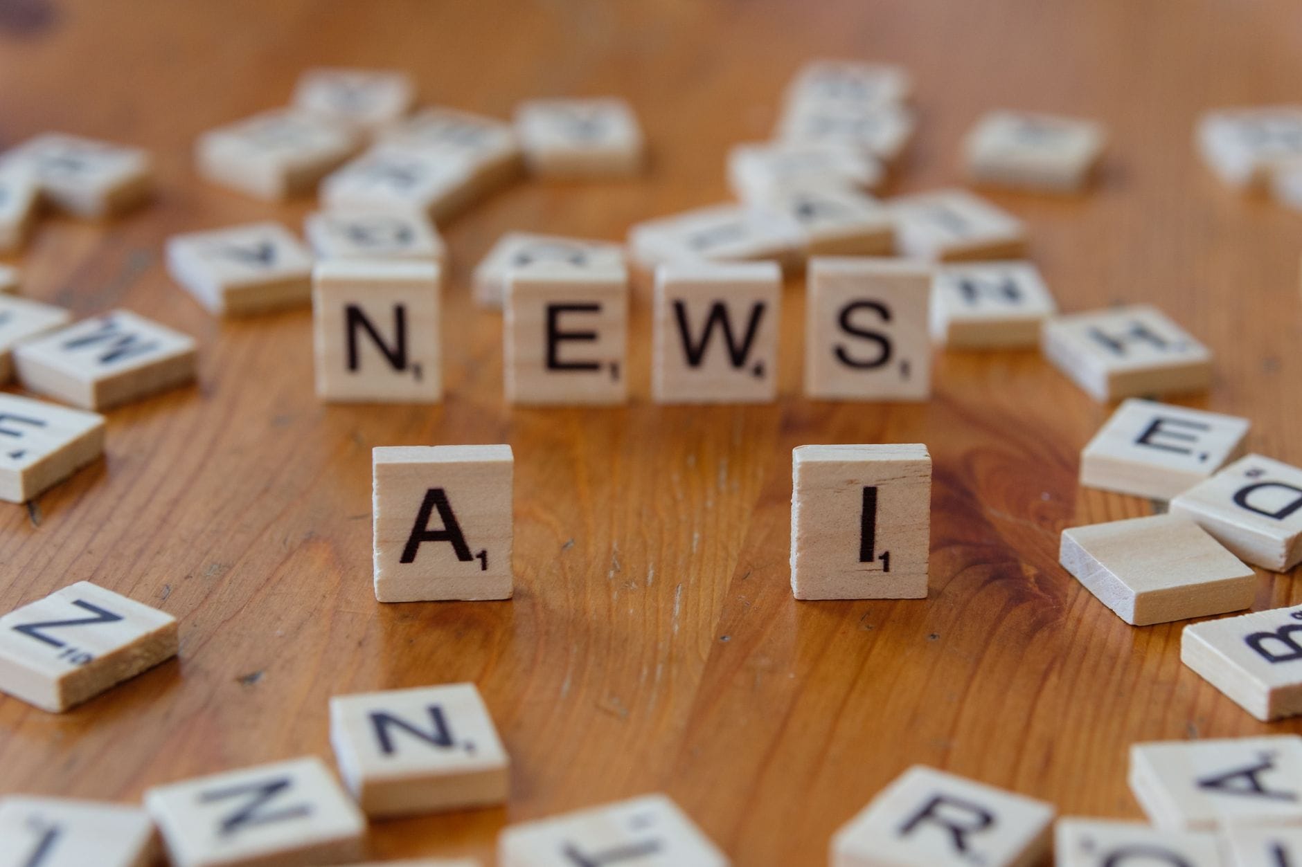 Drewniane klocki scrabble tworzące napisy AI i NEWS